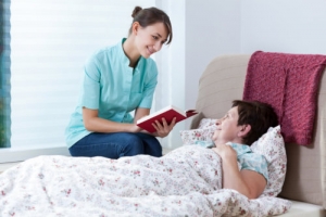 caregiver reading books to senior woman